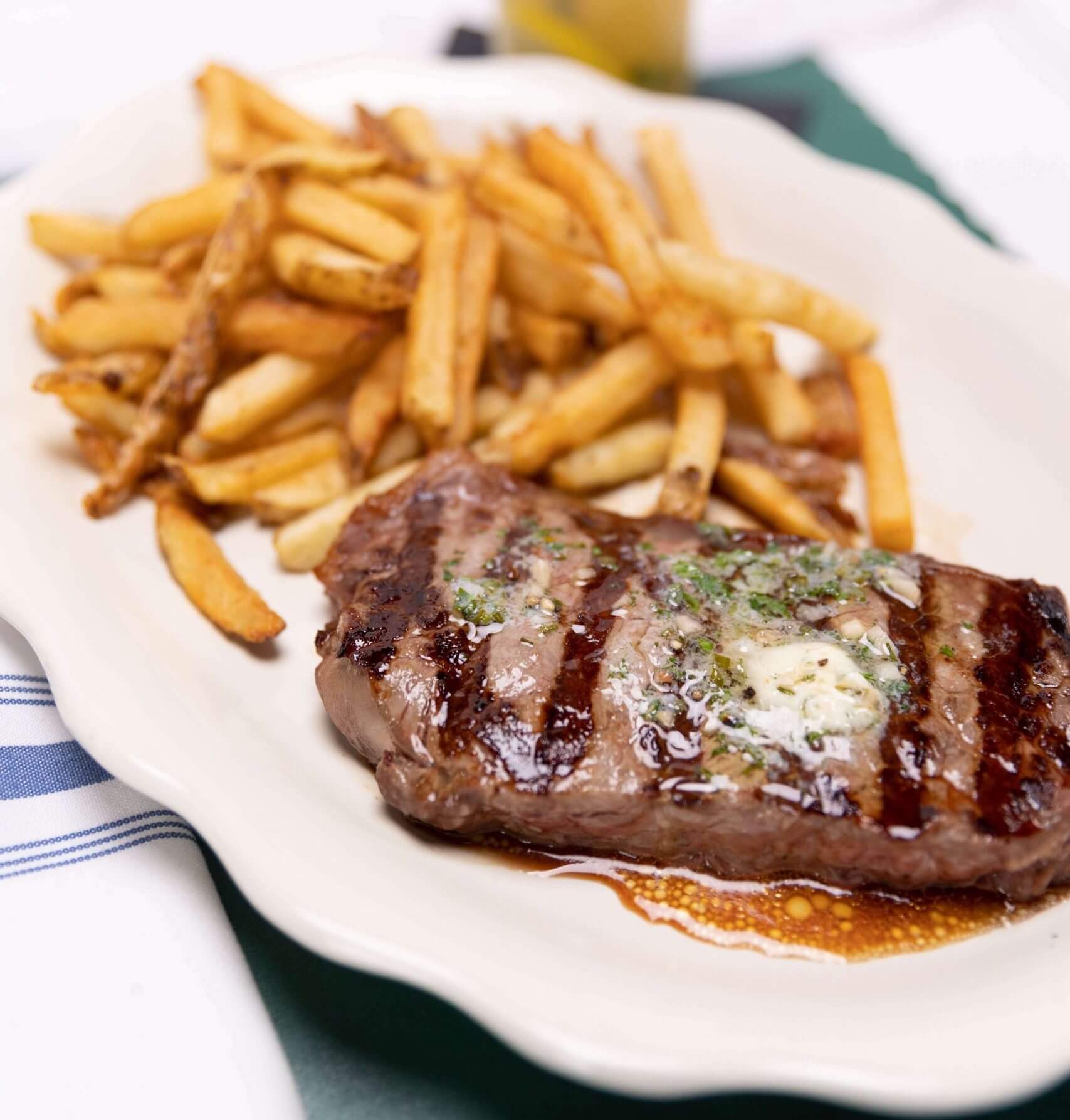 A steak and fries on a white plate
