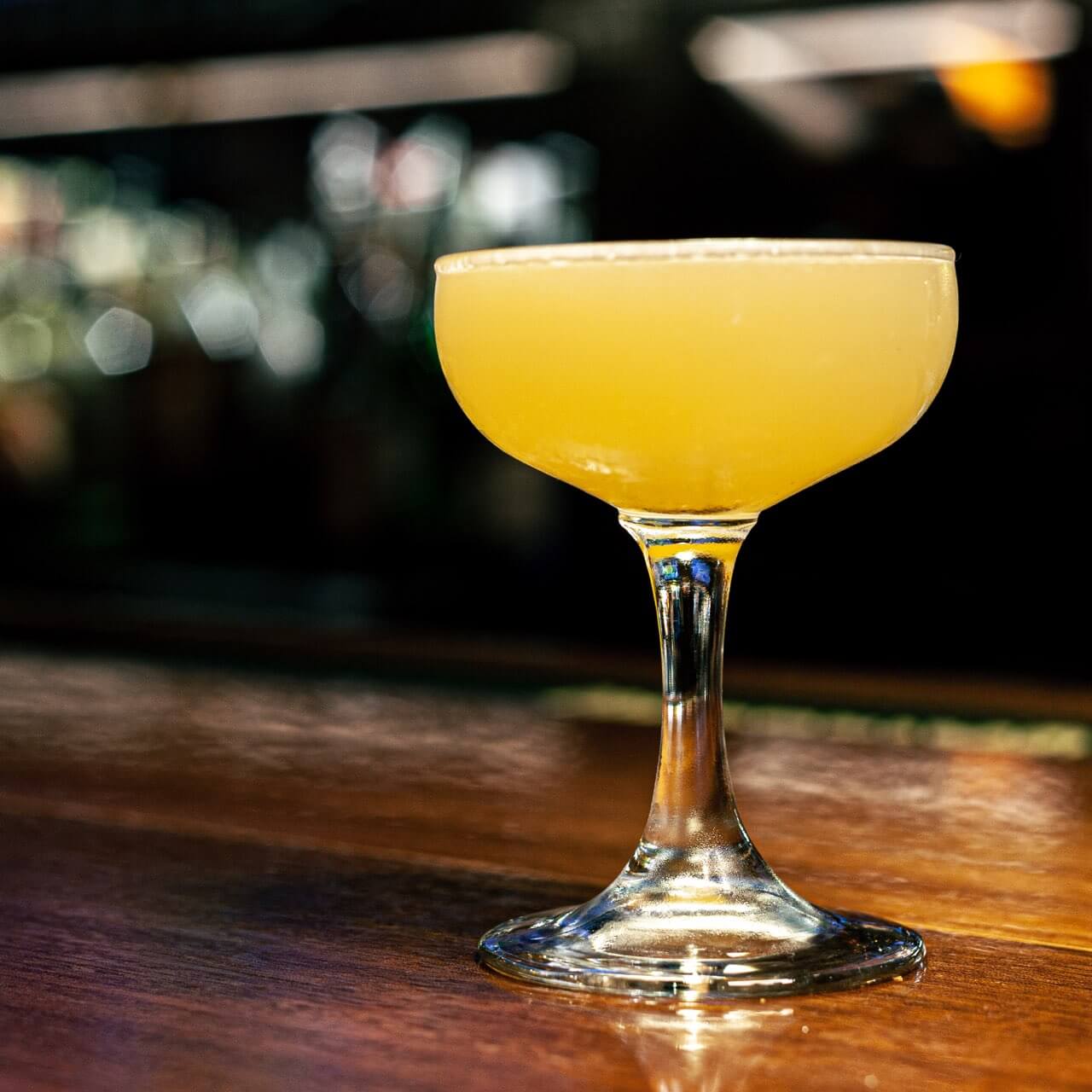 Yellow cocktail on a dark wood table