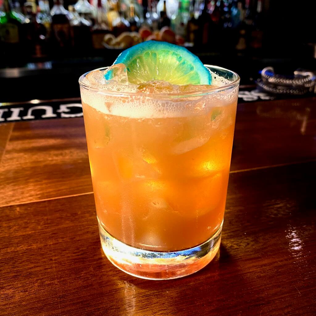 Orange cocktail with a blue fruit slice