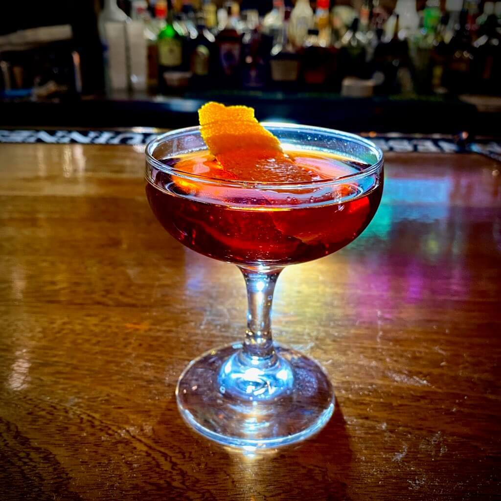 Red cocktail with a orange peel