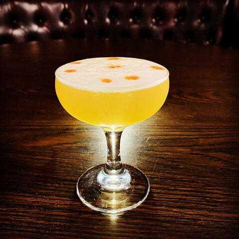 Yellow cocktail on a dark wood table